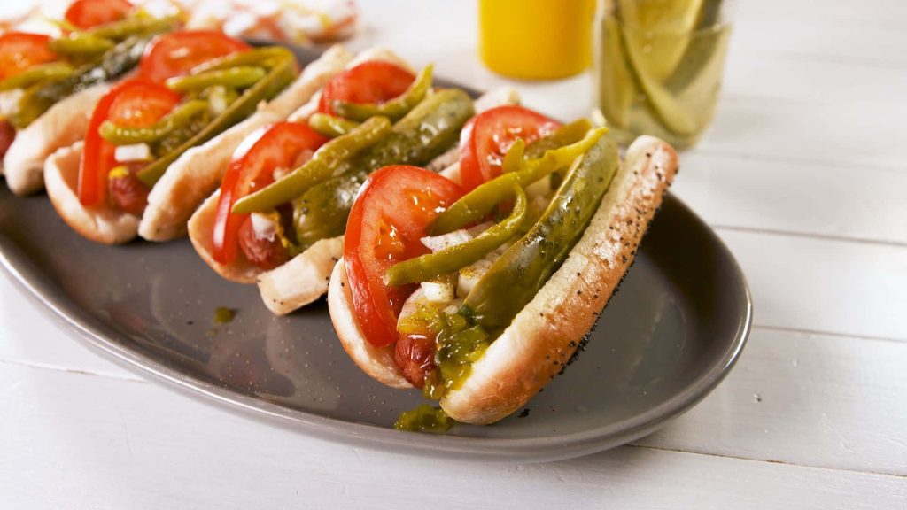 Close-up of Chicago-style hot dogs with poppy seed buns tomato sport peppers and relish Wallpaper