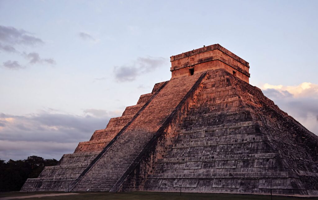 Chichén Itzá pyramid at sunset with warm light highlighting ancient Mayan architecture Wallpaper
