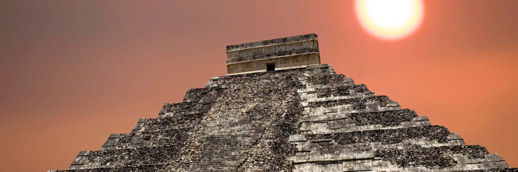 Chichén Itzá pyramid at sunset with warm pastel orange sky ancient Mayan architecture wallpaper
