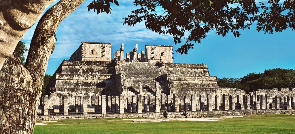 Chichén Itzá ancient pyramid at sunset with golden light vibrant blue sky and lush greenery Wallpaper