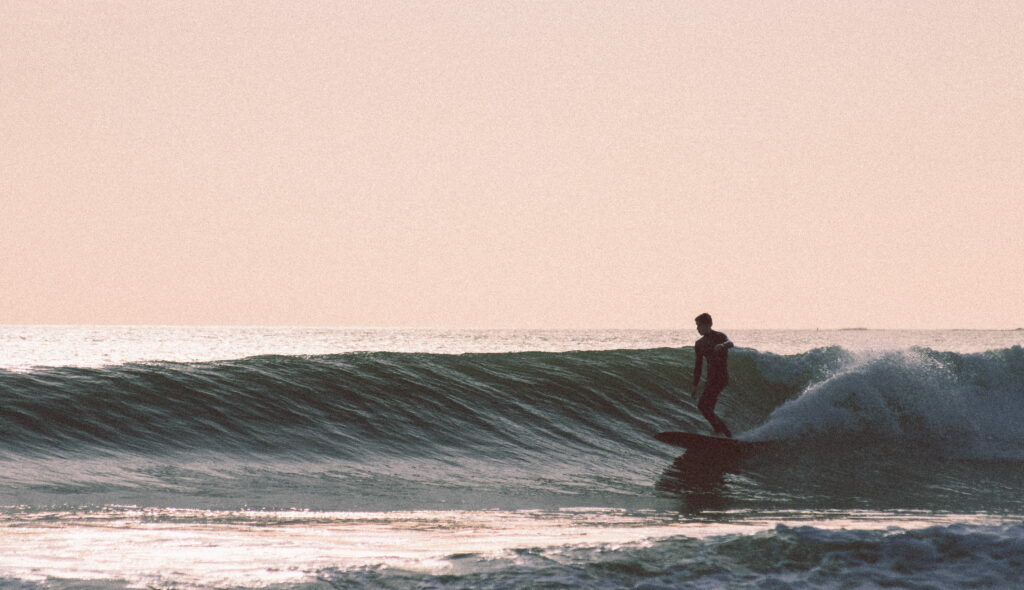 Surfing the Waves of Chill: A Man's Longboard Adventure in the Sun - Wallpaper Background Photo.