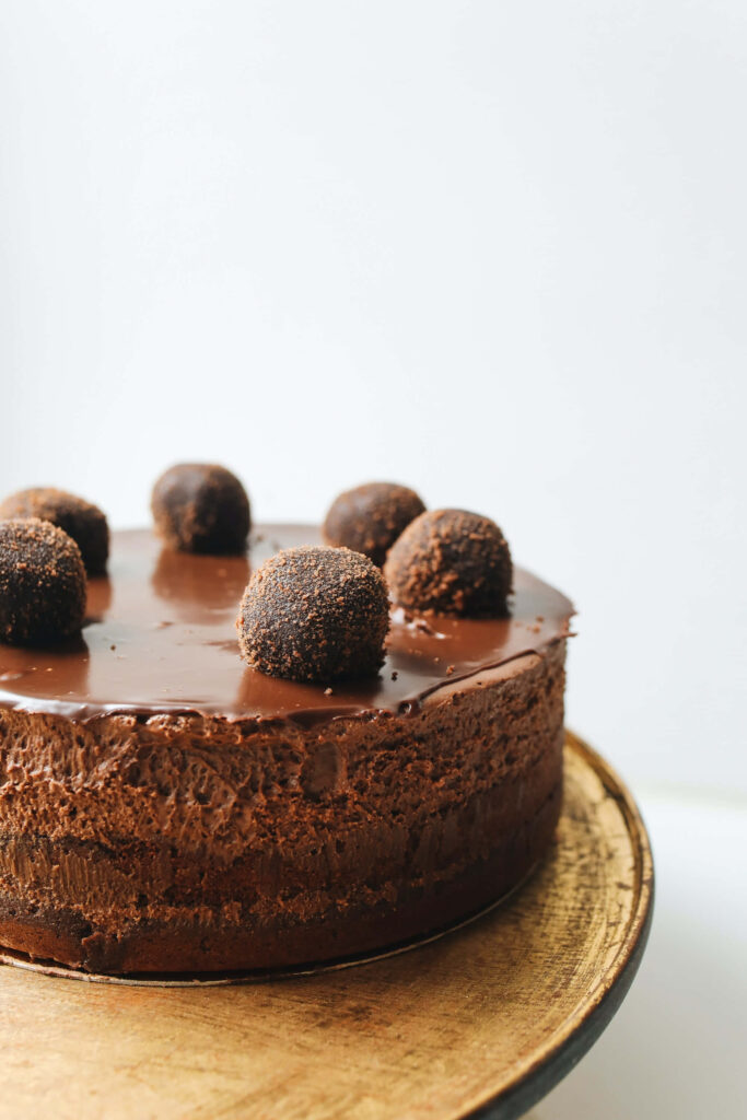 Chocolate birthday cake wallpaper with glossy glaze and truffle decorations on light background