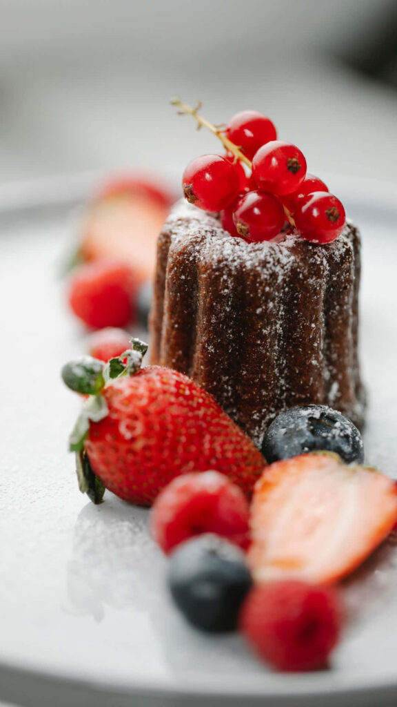 Chocolate dessert with powdered sugar and fresh berries on white plate iPhone wallpaper