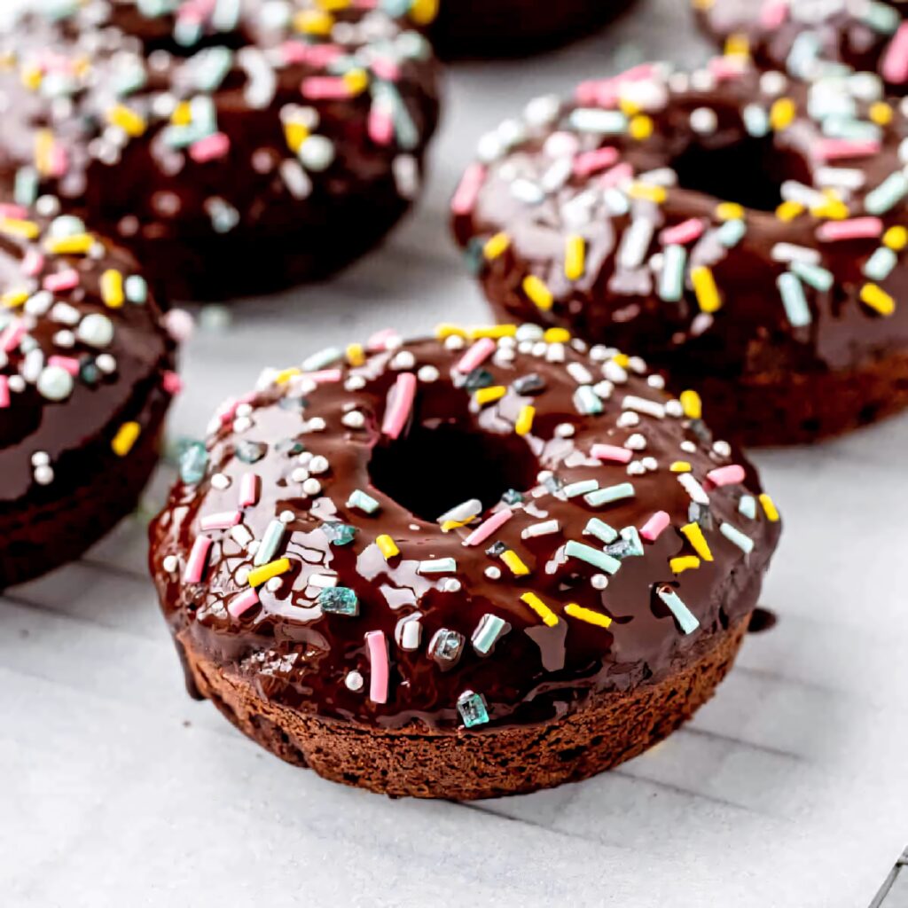 Close-up of chocolate-glazed donuts with colorful sprinkles dessert-themed wallpaper background