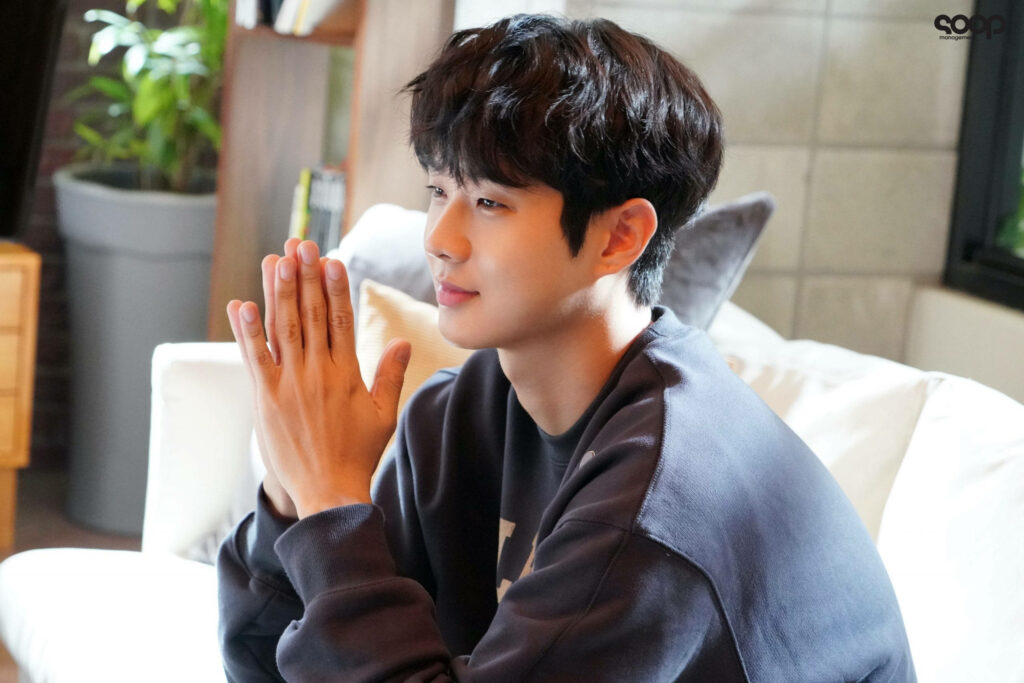 Choi Woo-shik thoughtful glance cozy modern living room natural tones soft lighting wallpaper background