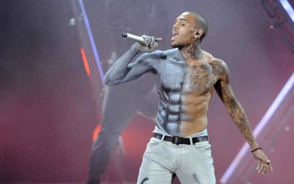 Chris Brown performing energetically on stage with vivid tattoos and dynamic body paint wallpaper
