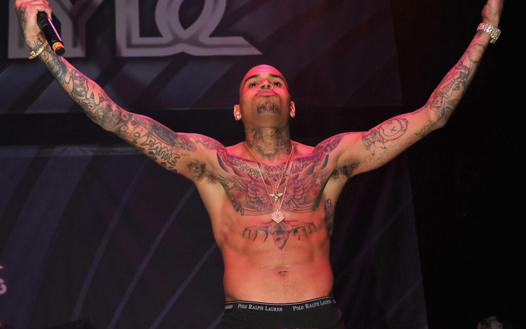 Chris Brown shirtless tattooed performing on stage vibrant lighting dynamic music wallpaper background