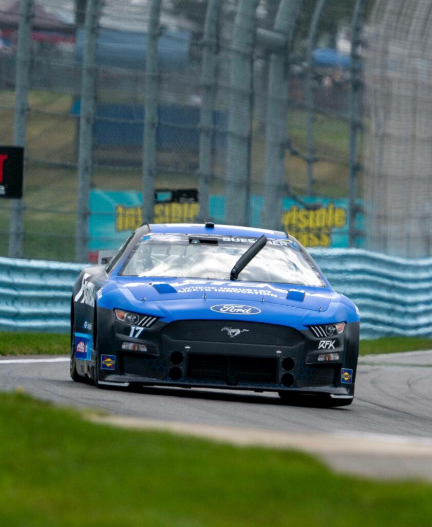 Chris Buescher blue Ford Mustang race car speeding on track intense high stakes racing wallpaper