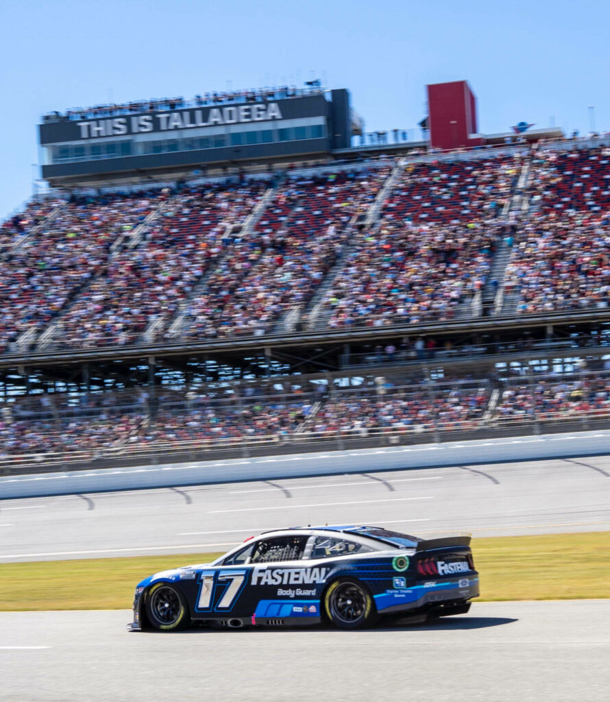Chris Buescher Ford Mustang racing fast past grandstands at Talladega speedway wallpaper