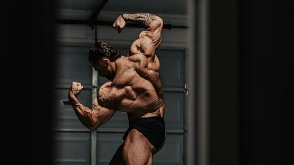 Chris Bumstead flexes defined back muscles in dramatic lighting bodybuilding wallpaper background