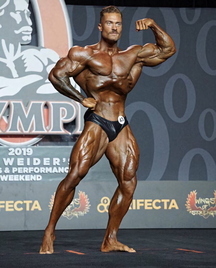 Chris Bumstead classic one bicep pose showing sculpted muscles and symmetry on stage background Wallpaper
