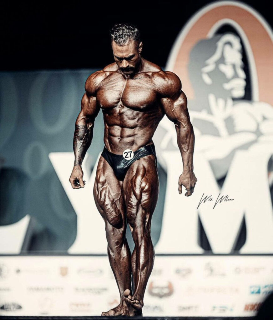 Chris Bumstead on stage showcasing sculpted muscles classic physique bodybuilding competition Wallpaper