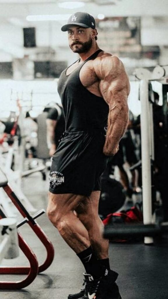 Chris Bumstead muscular side profile gym wallpaper showing dedication to bodybuilding strength