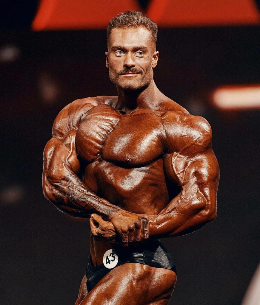 Chris Bumstead tanned side chest pose showcasing muscular physique and defined muscles wallpaper background