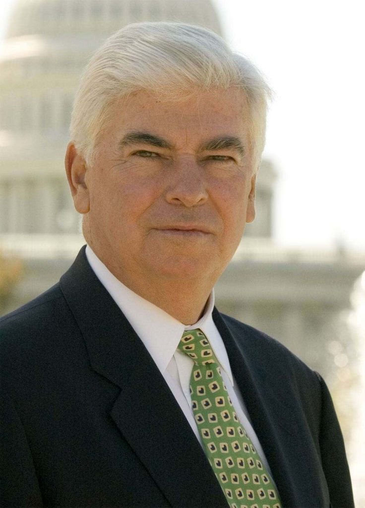 Formal portrait of former Senator Chris Dodd in suit with US Capitol blurred background bright lighting Wallpaper