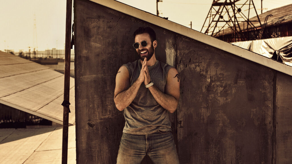 Chris Evans casual sleeveless shirt sunglasses industrial backdrop warm golden lighting wallpaper