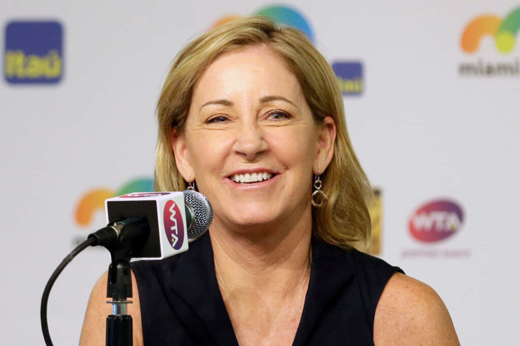 Chris Evert speaking at a press event smiling with sports logo backdrop in a professional setting Wallpaper