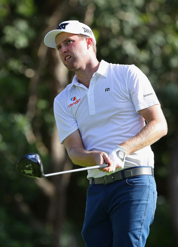 Chris Kirk mid-swing on lush golf course showing focus athletic form and branded apparel Wallpaper