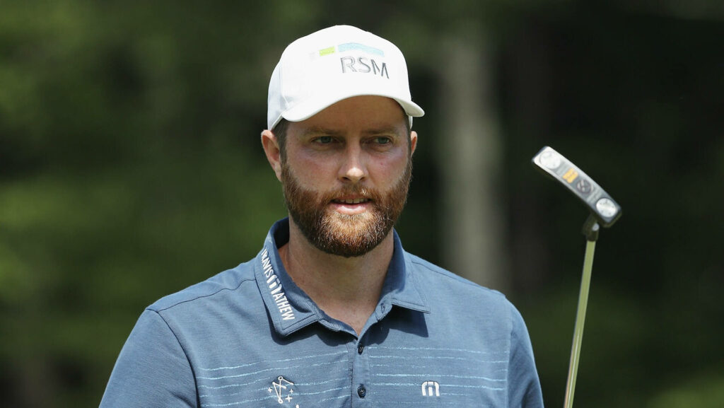 Chris Kirk focused outdoors on golf course wearing white RSM cap blue shirt holding putter wallpaper