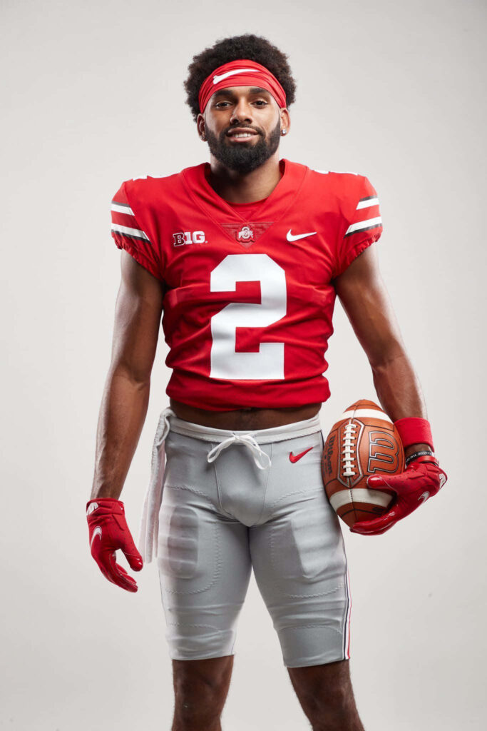 Chris Olave in red gray Ohio State uniform holding football confident athletic portrait wallpaper