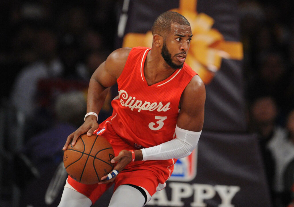 Chris Paul in Los Angeles Clippers jersey dribbling basketball with intense focus in arena Wallpaper