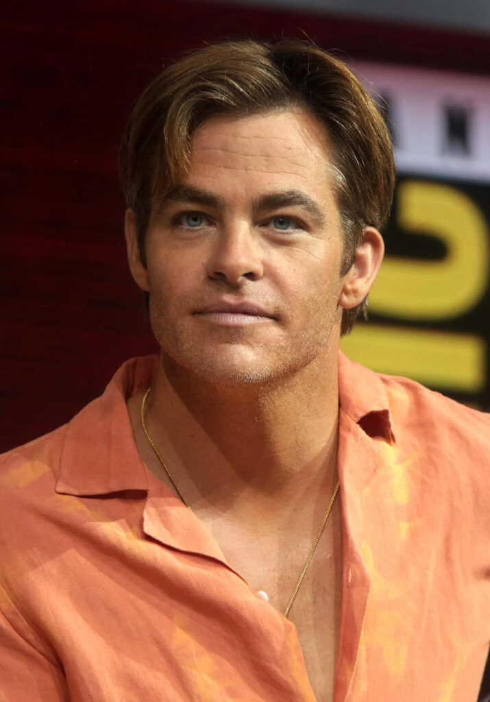 Chris Pine candid portrait wearing light orange shirt and gold chain with warm blurred background Wallpaper