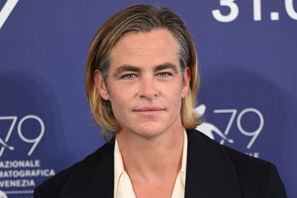Chris Pine in stylish suit with blonde hair against deep blue background soft natural lighting Wallpaper