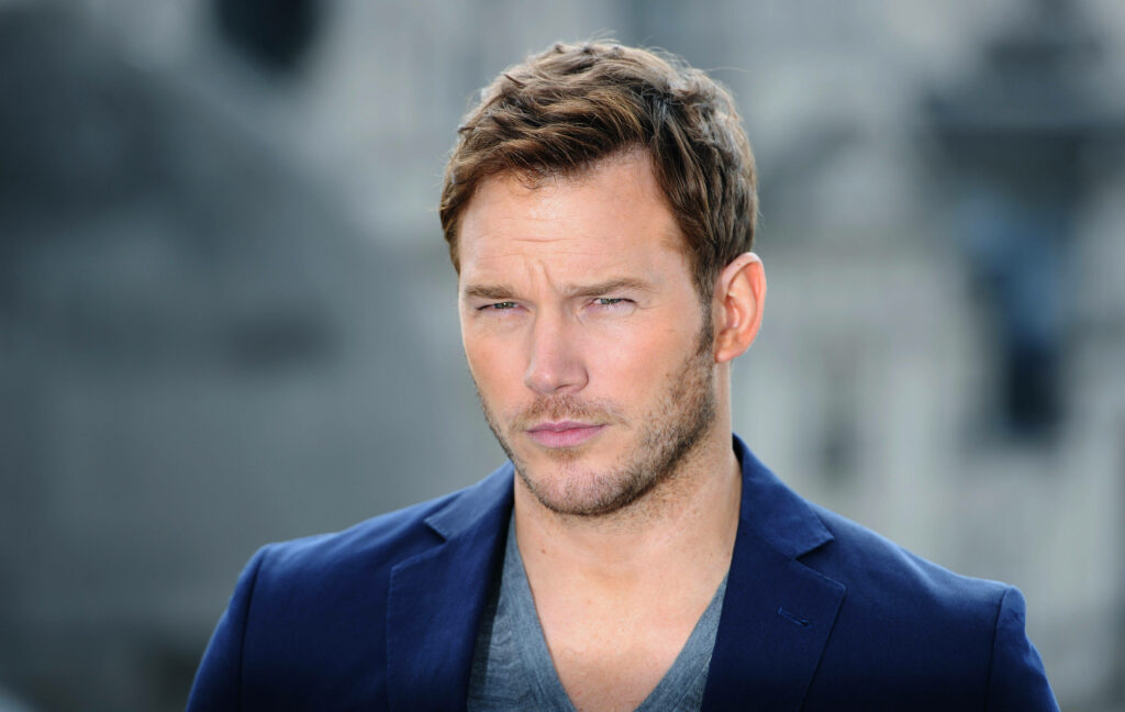Chris Pratt confident portrait in navy blazer with blurred cityscape background natural light Wallpaper