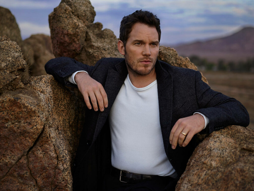 Chris Pratt stylish celebrity wallpaper in rugged outdoor setting with dark blazer and natural rocks