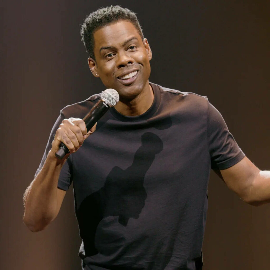 Chris Rock animated wallpaper with microphone vibrant stage presence warm tones background