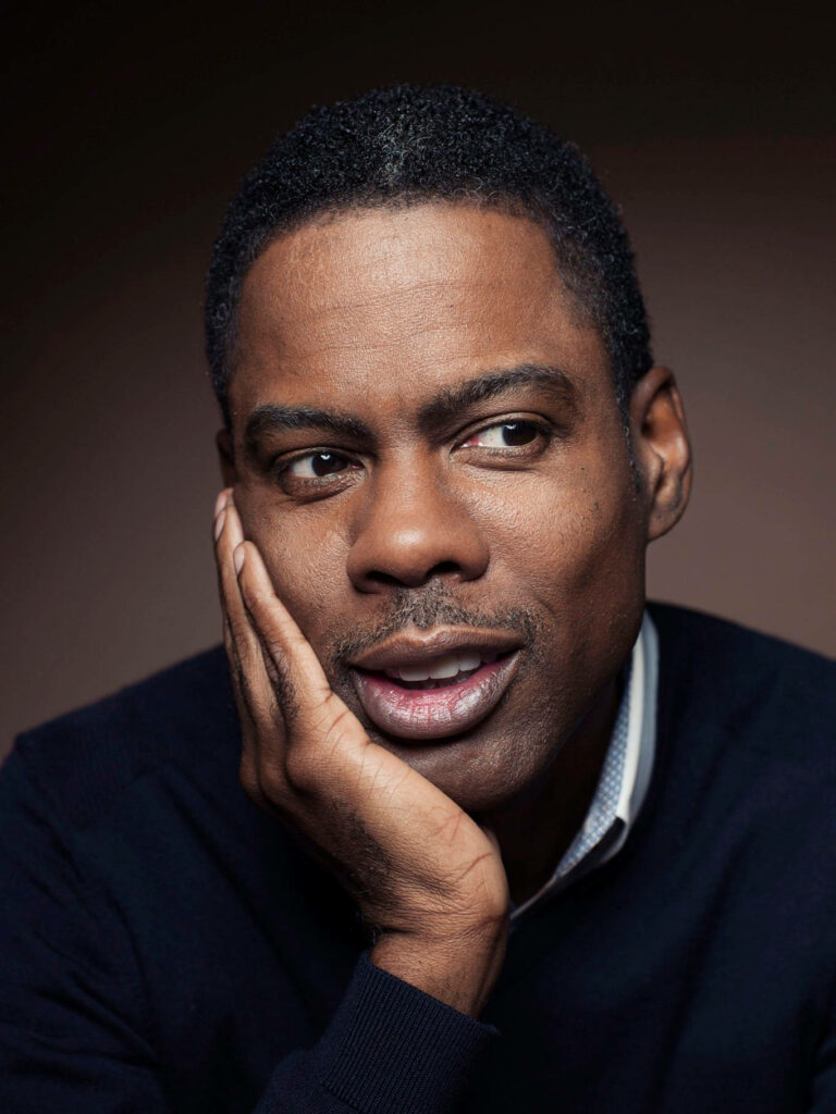 Close-up portrait of comedian Chris Rock thoughtful expression soft lighting dark background Wallpaper
