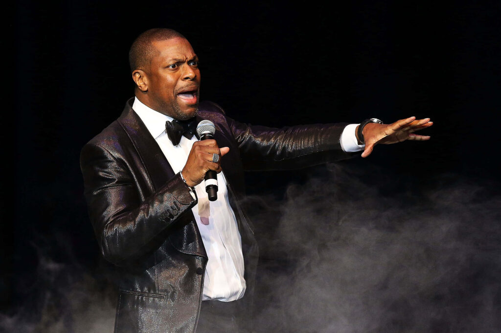 Chris Tucker performing on stage in black tuxedo with bow tie dramatic lighting and stage fog Wallpaper