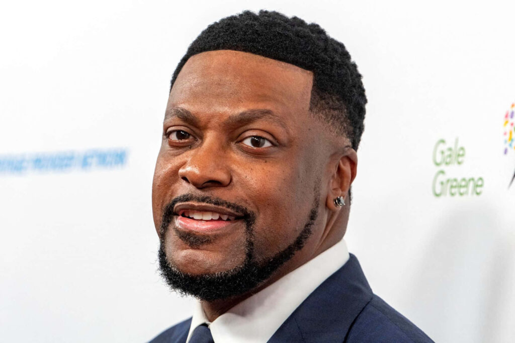 Chris Tucker smiling in dark suit with signature beard and stylish haircut on light background Wallpaper