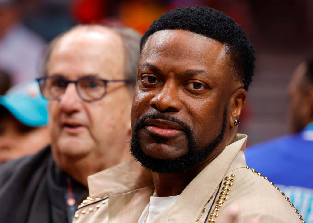 Chris Tucker in stylish beige studded jacket at public event with blurred crowd background Wallpaper