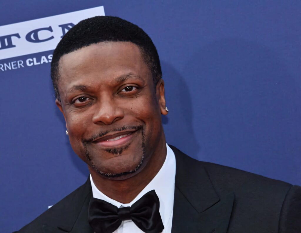 Chris Tucker in black tuxedo smiling against deep blue background high resolution wallpaper