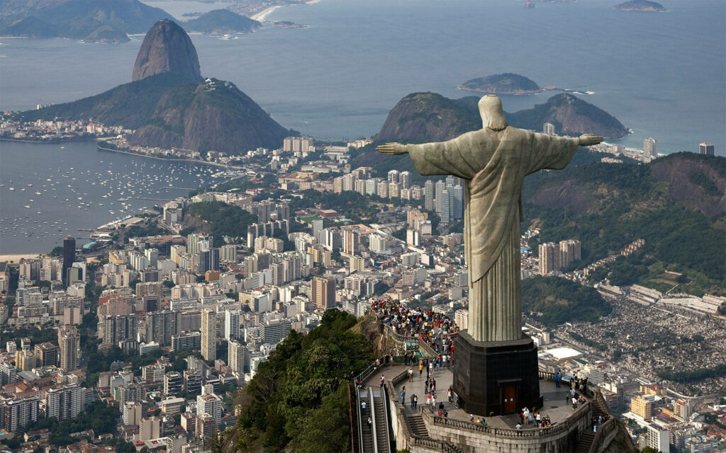 The Majestic Christ the Redeemer Statue Overlooking Rio's Splendid Urban Landscape and Scenic Mountains Wallpaper