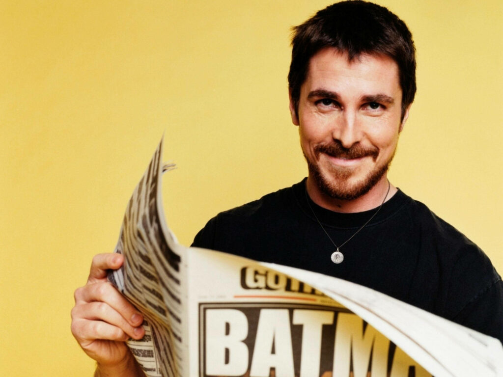 Christian Bale smiling warmly holding newspaper bright yellow background photoshoot wallpaper