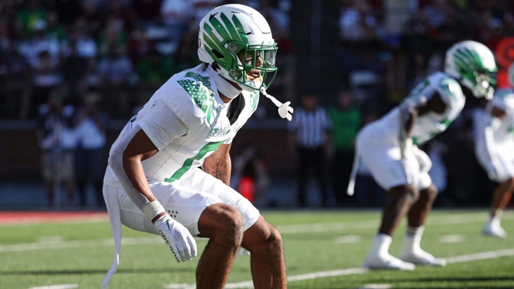 Christian Gonzalez football player in white green uniform with winged helmet in sunlit stadium Wallpaper
