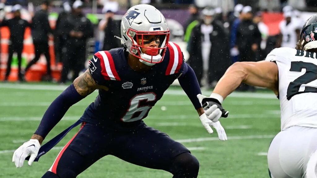 Christian Gonzalez New England Patriots in action defense navy blue red uniform stadium background Wallpaper