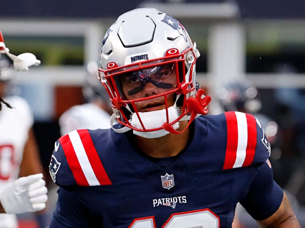 Christian Gonzalez NFL wallpaper Patriots uniform dynamic pose intense focus gridiron action background