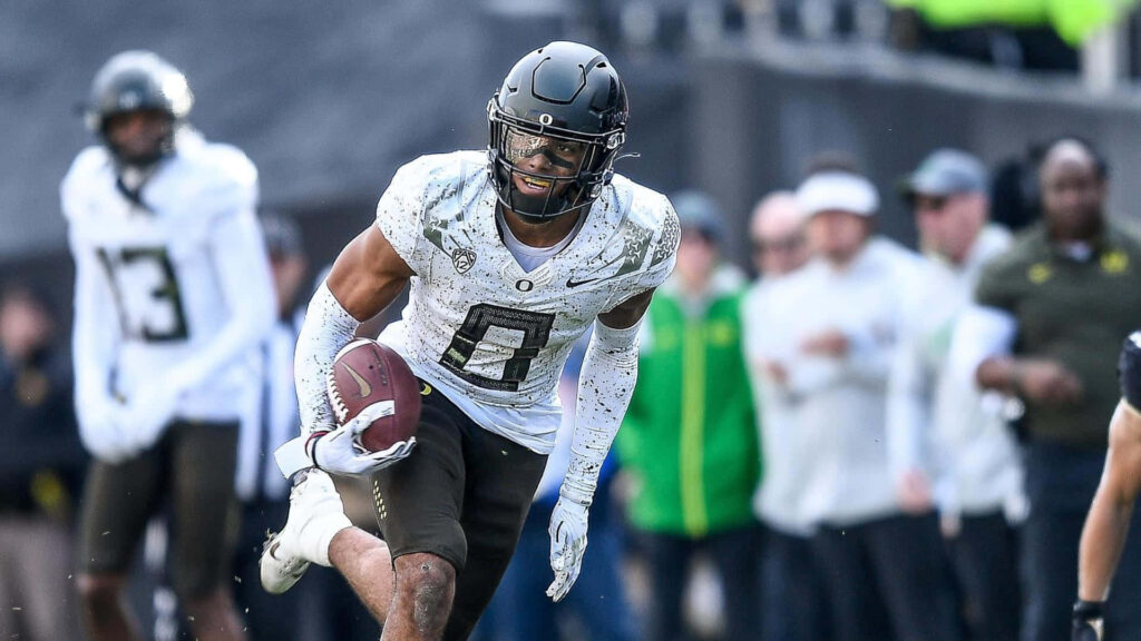 Christian Gonzalez Oregon Ducks football player charging down field in dynamic stadium action Wallpaper
