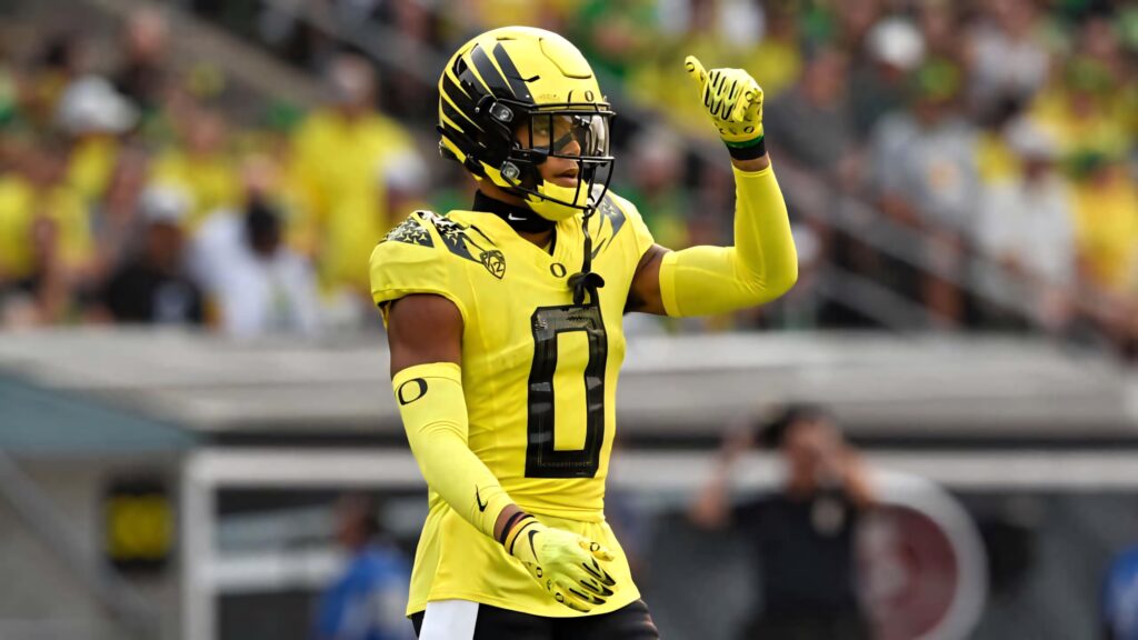 Christian Gonzalez in yellow black football uniform with helmet on vibrant stadium field background Wallpaper