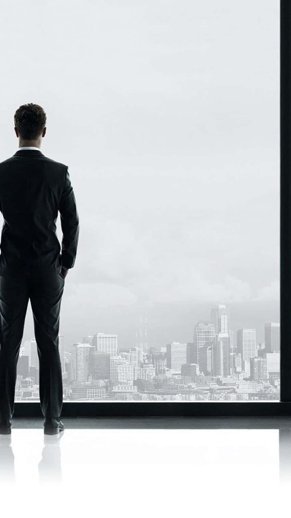 Christian Grey in tailored suit overlooking city skyline moody monochrome cinematic wallpaper