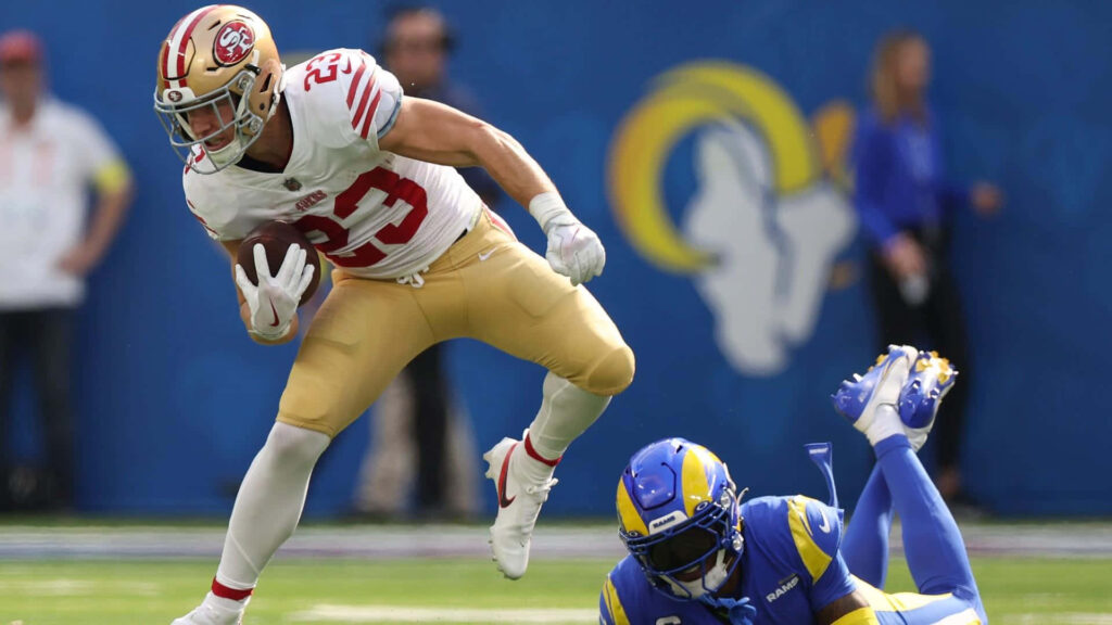 Christian McCaffrey in 49ers jersey number 23 evades Los Angeles Rams defender NFL action wallpaper