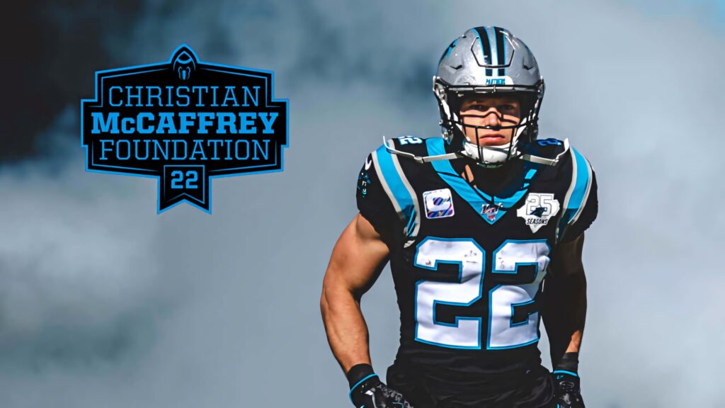 Christian McCaffrey in Carolina Panthers uniform focused on field with smoky football action backdrop Wallpaper
