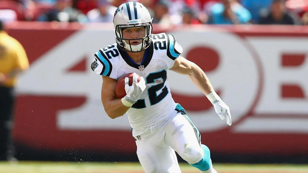 Christian McCaffrey Carolina Panthers running back mid-run in white blue uniform on football field Wallpaper