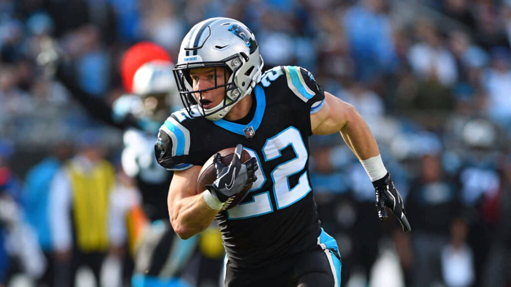 Christian McCaffrey sprinting in Carolina Panthers uniform showcasing speed and determination Wallpaper