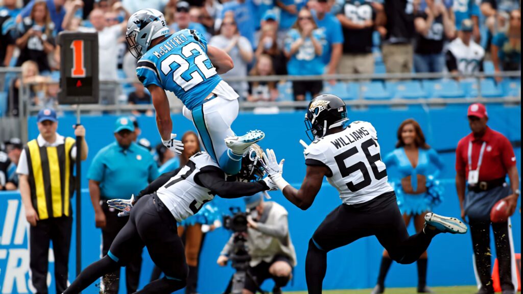 Christian McCaffrey leaps over Jaguars defender Williams in intense Panthers vs Jaguars game action Wallpaper