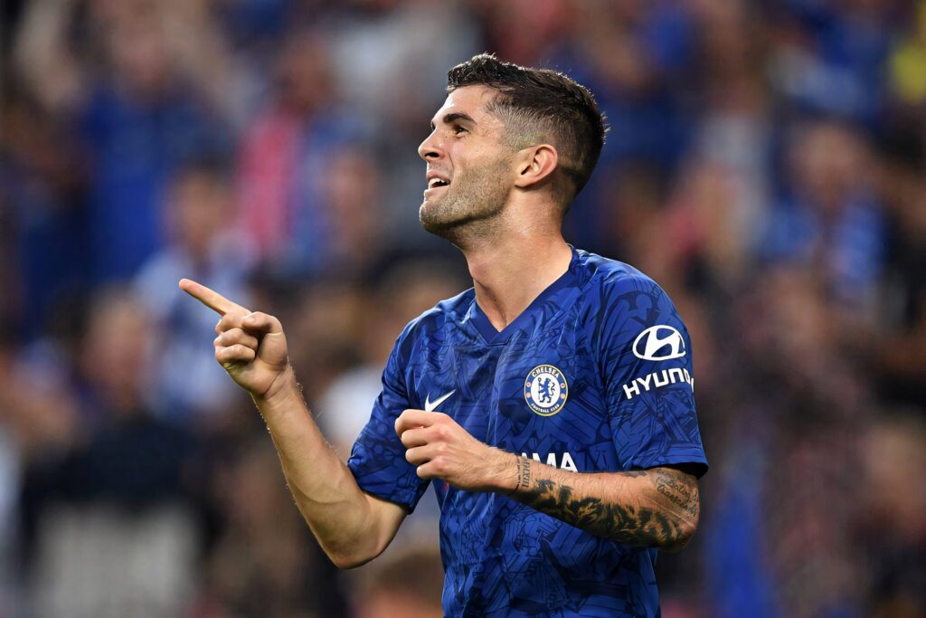 Christian Pulisic in Chelsea blue kit confidently pointing during intense soccer match action Wallpaper