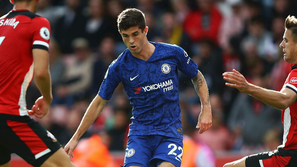 Christian Pulisic in Chelsea kit skillfully dribbling past opponents in intense football match Wallpaper